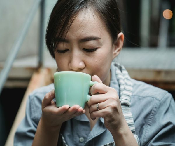 A woman starting her day with a mindful cup of tea and stretching.